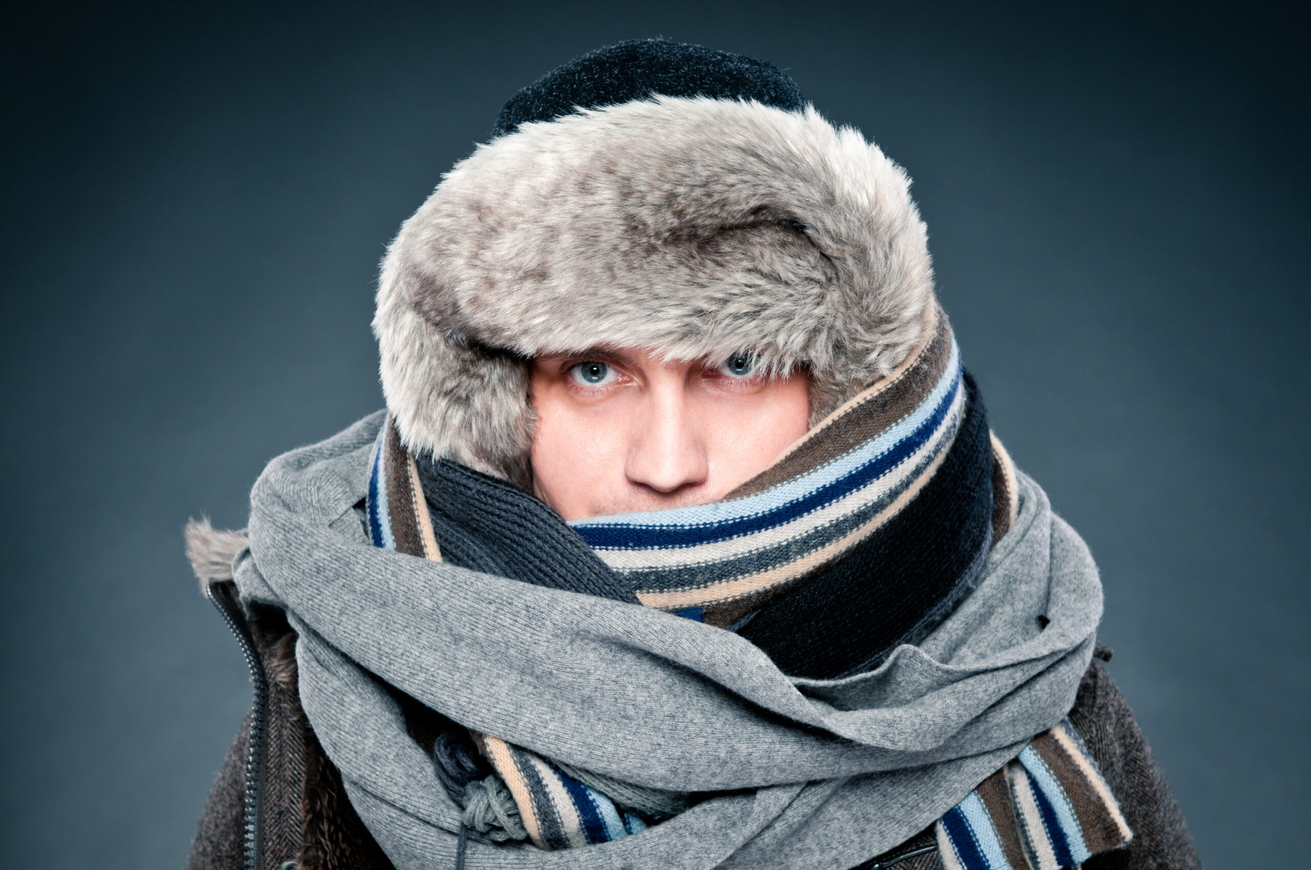 Man in winter clothes is tightly bundled up, cap, scarves